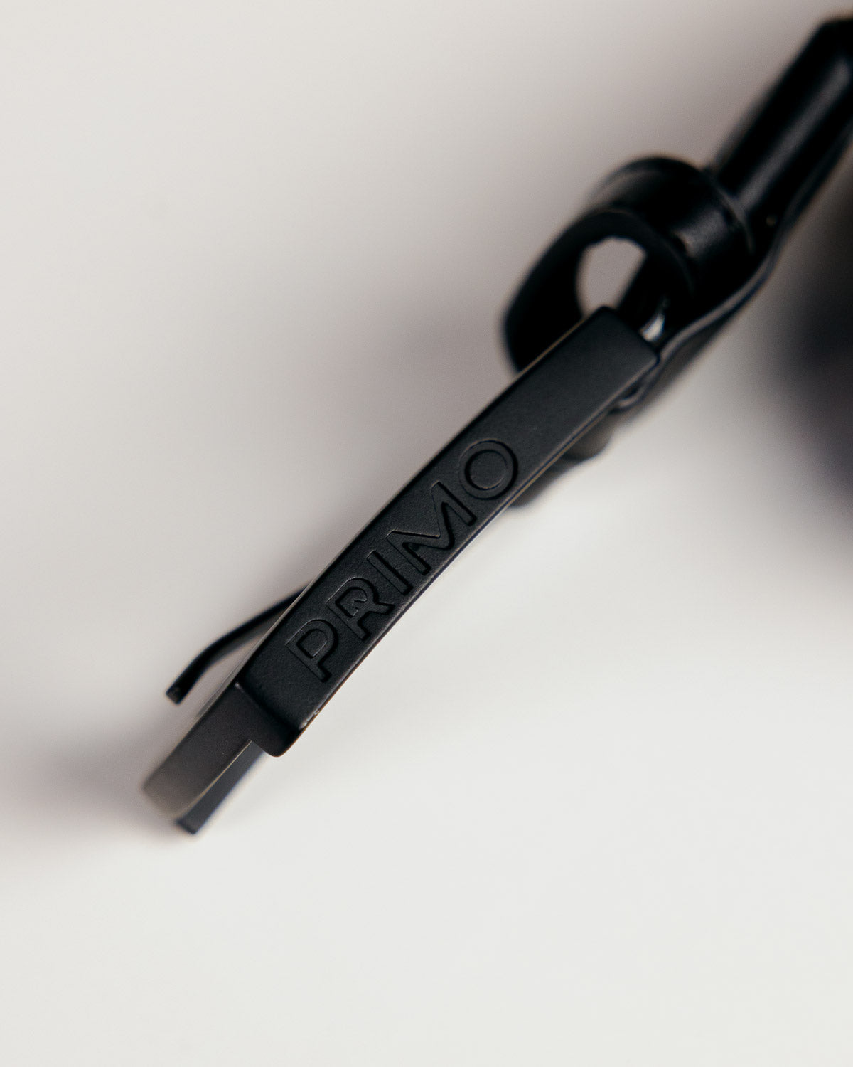 Primo Braided Golf Belt Black — embossed PRIMO leather tip close up